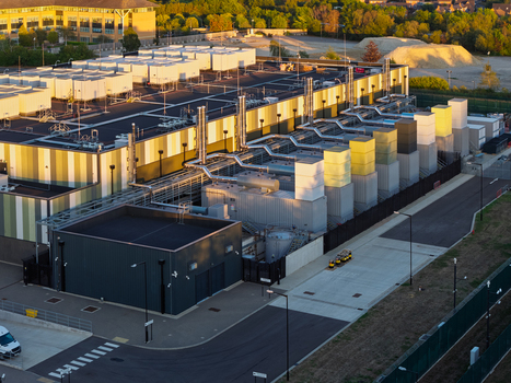 Aerial view of a large data center facility featuring industrial cooling units complex piping systems and modern rooftops in the United Kingdom. Aerial view of a large data center facility featuring industrial cooling units complex piping systems and modern rooftops in the United Kingdom.