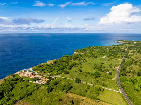 Aerial view of the coastal landscape in Rio San Juan featuring green fields a road and a house on the cliff edge in Rio San Juan Maria Trinidad Sanchez Dominican Republic. Aerial view of the coastal landscape in Rio San Juan featuring green fields a road and a house on the cliff edge in Rio San Juan Maria Trinidad Sanchez Dominican Republic.