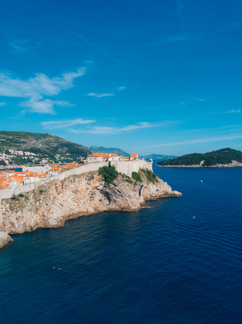 View of the historic Dubrovnik Old Town walls on a rocky cliff overlooking the blue Adriatic Sea with Lokrum Island in the distance Dubrovnik Dubrovnik Neretva County Croatia. View of the historic Dubrovnik Old Town walls on a rocky cliff overlooking the blue Adriatic Sea with Lokrum Island in the distance Dubrovnik Dubrovnik Neretva County Croatia.
