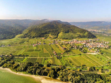 Aerial view of the Wachau valley featuring lush vineyards a charming village and rolling hills along the Danube river in Krems District Lower Austria Austria. Aerial view of the Wachau valley featuring lush vineyards a charming village and rolling hills along the Danube river in Krems District Lower Austria Austria.