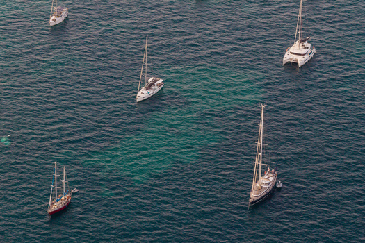 Aerial view of sailboats and a catamaran anchored in the clear turquoise waters off the coast of Antibes Provence Alpes Cote d Azur France. Aerial view of sailboats and a catamaran anchored in the clear turquoise waters off the coast of Antibes Provence Alpes Cote d Azur France.