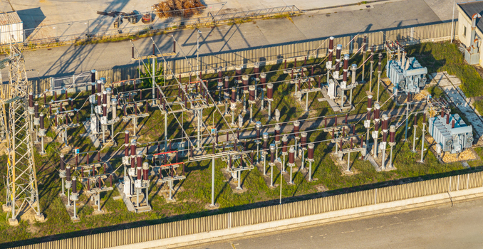 Aerial view of electrical substation equipment with transformers and power lines within a fenced industrial facility in Italy. Aerial view of electrical substation equipment with transformers and power lines within a fenced industrial facility in Italy.