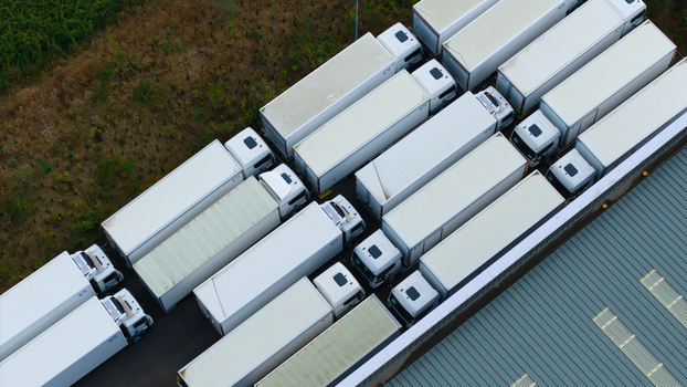 Aerial view of a logistics hub with rows of white HGVs parked beside industrial warehouses in Bedford England United Kingdom. Aerial view of a logistics hub with rows of white HGVs parked beside industrial warehouses in Bedford England United Kingdom.