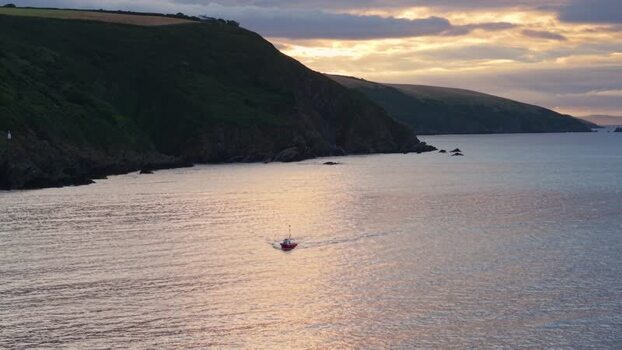 Aerial view of a red boat in a calm bay at sunset United Kingdom. Aerial view of a red boat in a calm bay at sunset United Kingdom.