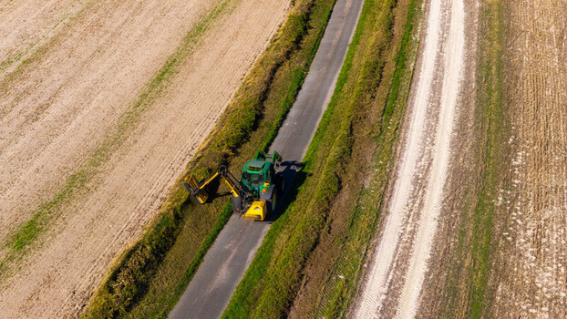 Aerial view of a tractor trimming hedges along a rural road at Pepperbox Hill Salisbury England United Kingdom. Aerial view of a tractor trimming hedges along a rural road at Pepperbox Hill Salisbury England United Kingdom.