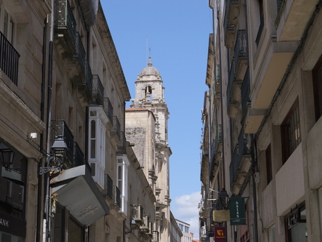 View of the historic Igrexa da Santa Eufemia tower rising above a narrow street lined with traditional stone buildings and balconies in Ourense Ourense Spain.