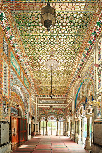 View of the ornate interior of Jamia Masjid Bhong Sharif featuring intricate tile work geometric ceiling patterns and hanging lanterns in Bhong Punjab Pakistan.