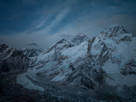 Aerial view of snow capped peaks of Mount Everest with rugged glaciers and dramatic twilight sky over the Himalayas in Nepal.