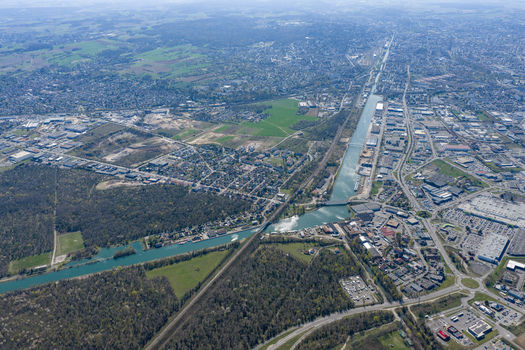 Aerial view of a canal cutting through the landscape contrasting with the surrounding greenery and urban sprawl Sausheim Grand Est France.
