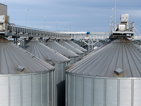 Aerial view of industrial grain silos with corrugated metal surfaces and connecting catwalks at a storage facility in Poland. Aerial view of industrial grain silos with corrugated metal surfaces and connecting catwalks at a storage facility in Poland.