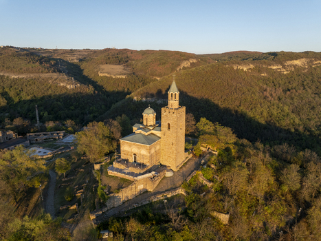 Aerial view of Tsarevets Fortress with its historic stone church tower and surrounding lush hills under golden hour light in Veliko Tarnovo Veliko Tarnovo Bulgaria. Aerial view of Tsarevets Fortress with its historic stone church tower and surrounding lush hills under golden hour light in Veliko Tarnovo Veliko Tarnovo Bulgaria.