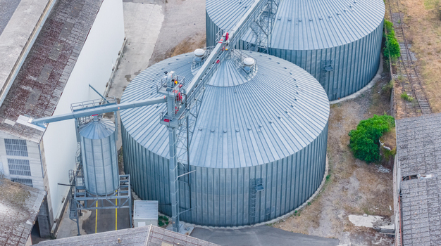Aerial view of large galvanized grain silos with conveyor systems at an agricultural storage facility in Le Pouzin Auvergne Rhone Alpes France.