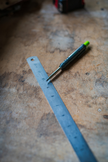 View of a metal ruler and a mechanical pencil resting on a weathered wooden workbench in Looe Cornwall United Kingdom. View of a metal ruler and a mechanical pencil resting on a weathered wooden workbench in Looe Cornwall United Kingdom.