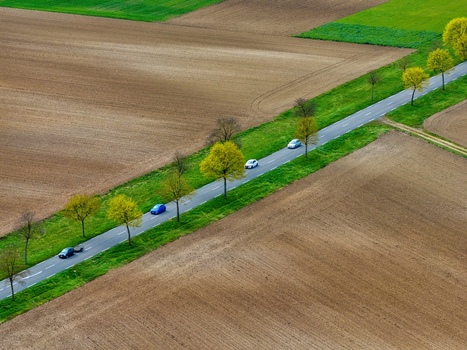 Aerial view of a straight road cutting through fields lined with trees and cars a beautiful contrast of green and brown hues Neuf Brisach Grand Est France.