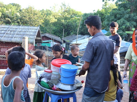 Cox s Bazar Bangladesh 19 July 2026 View of Rohingya refugee camp with a man serving food to children and families in a makeshift settlement.