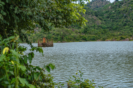 View of Lamingo Dam featuring a calm lake surrounded by lush green hills and dense vegetation under a cloudy sky in Jos Plateau Nigeria.