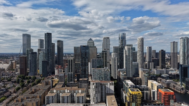 London United Kingdom 16 June 2026 Aerial view of the modern skyscrapers of Canary Wharf financial district under a cloudy blue sky.