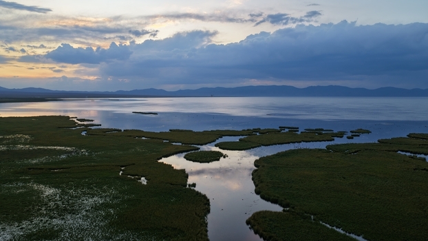 Aerial view of Song Kul lake at sunset with marshy wetlands and distant mountains in Naryn Region Kyrgyzstan. Aerial view of Song Kul lake at sunset with marshy wetlands and distant mountains in Naryn Region Kyrgyzstan.