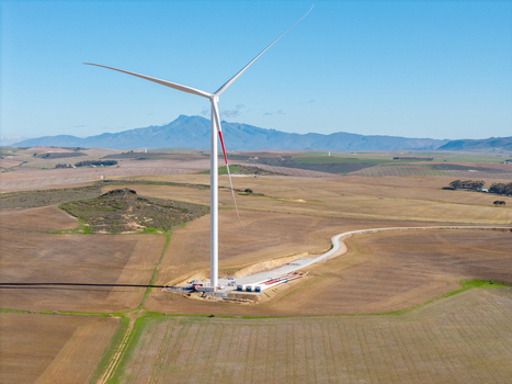 Aerial view of a large white wind turbine standing in a vast agricultural landscape with rolling hills and distant mountains in Swellendam Western Cape South Africa. Aerial view of a large white wind turbine standing in a vast agricultural landscape with rolling hills and distant mountains in Swellendam Western Cape South Africa.