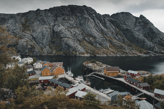 Nusfjord Norway 07 September 2022 View of Nusfjord with its iconic yellow and red wooden rorbu cabins nestled against dramatic rocky cliffs and the calm waters of the fjord. Nusfjord Norway 07 September 2022 View of Nusfjord with its iconic yellow and red wooden rorbu cabins nestled against dramatic rocky cliffs and the calm waters of the fjord.