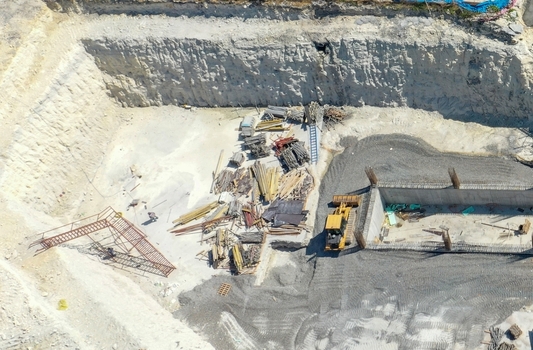 Aerial view of a deep construction site excavation with a yellow bulldozer concrete foundation walls and building materials in Avcilar Istanbul Turkiye. Aerial view of a deep construction site excavation with a yellow bulldozer concrete foundation walls and building materials in Avcilar Istanbul Turkiye.