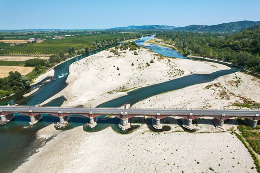 Aerial view of Ponte Crescentino spanning the Po River during a severe drought with exposed riverbed and dry gravel banks in Verrua Savoia Piemonte Italy. Aerial view of Ponte Crescentino spanning the Po River during a severe drought with exposed riverbed and dry gravel banks in Verrua Savoia Piemonte Italy.