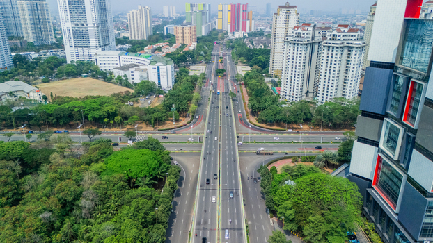 Aerial view of a busy multi lane highway intersection surrounded by modern high rise buildings and lush green trees in Jakarta Indonesia. Aerial view of a busy multi lane highway intersection surrounded by modern high rise buildings and lush green trees in Jakarta Indonesia.