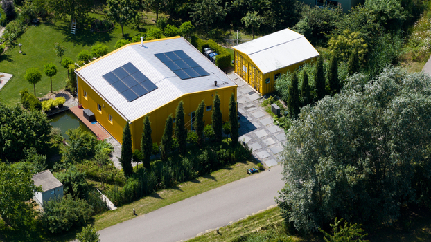 Aerial view of Ecodorp Bolderburen featuring a yellow house with solar panels a small pond and lush greenery in Almere Flevoland Netherlands. Aerial view of Ecodorp Bolderburen featuring a yellow house with solar panels a small pond and lush greenery in Almere Flevoland Netherlands.