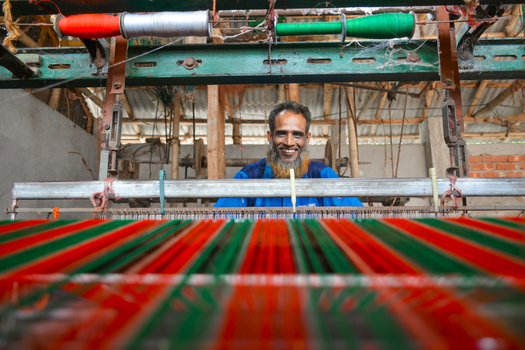 Joypurhat Bangladesh 22 September 2026 View of a man operating a traditional loom to weave vibrant red and green fabric in a workshop. Joypurhat Bangladesh 22 September 2026 View of a man operating a traditional loom to weave vibrant red and green fabric in a workshop.