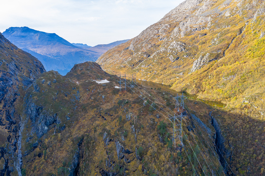 Aerial view of power lines stretching across a rugged mountainous landscape with autumn foliage and rocky terrain in Andalsnes More og Romsdal Norway. Aerial view of power lines stretching across a rugged mountainous landscape with autumn foliage and rocky terrain in Andalsnes More og Romsdal Norway.
