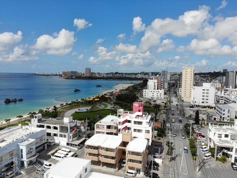 Aerial view of Arah Beach featuring a white sandy beach emerald green sea coastal promenade and surrounding urban buildings in Chatan Okinawa Japan. Aerial view of Arah Beach featuring a white sandy beach emerald green sea coastal promenade and surrounding urban buildings in Chatan Okinawa Japan.