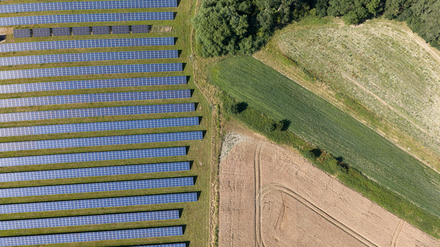Aerial view of a solar farm with rows of photovoltaic panels installed on green grass situated next to agricultural fields in Atherstone England United Kingdom. Aerial view of a solar farm with rows of photovoltaic panels installed on green grass situated next to agricultural fields in Atherstone England United Kingdom.