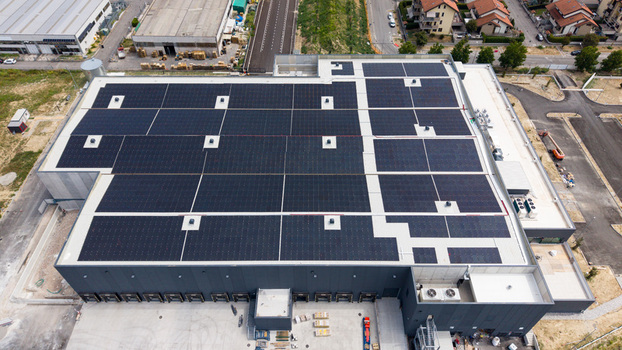 Aerial view of a modern logistics warehouse for fresh fruit and vegetable distribution featuring extensive rooftop solar panels ventilation and cooling systems in Melegnano Lombardy Italy.