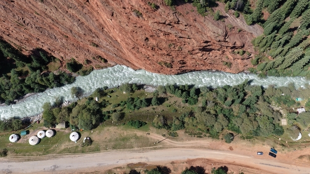 Aerial view of the Jety Oguz canyon with its distinctive red rock formations a rushing river lush pine forests and traditional yurts along the road in Jety Oguz Issyk Kul Region Kyrgyzstan. Aerial view of the Jety Oguz canyon with its distinctive red rock formations a rushing river lush pine forests and traditional yurts along the road in Jety Oguz Issyk Kul Region Kyrgyzstan.
