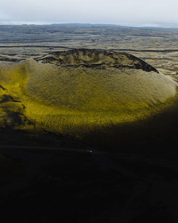 Aerial view of stark moss covered volcanic landscape where the vibrant yellow green hues contrast dramatically against the dark textured earth Skaftárhreppur Iceland. Aerial view of stark moss covered volcanic landscape where the vibrant yellow green hues contrast dramatically against the dark textured earth Skaftárhreppur Iceland.
