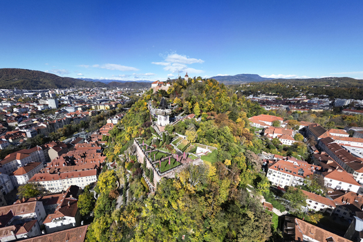 Aerial view of the vibrant Schlossberg hill crowned with its historic clock tower and fortress amidst the city s terracotta rooftops Graz Styria Austria.