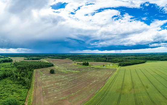 Aerial view of agricultural fields and forest patches under a dramatic cloudy sky in Latvia. Aerial view of agricultural fields and forest patches under a dramatic cloudy sky in Latvia.