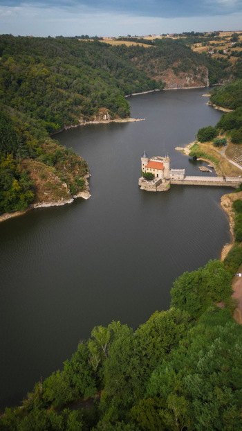 Aerial view of the Villerest dam standing guard over the tranquil waters framed by verdant forests under a brooding sky Saint Priest la Roche Auvergne Rh&ocirc;ne Alpes France.