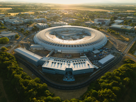 Aerial view of Diamond Light Source a circular synchrotron facility surrounded by greenery under golden hour light in Didcot United Kingdom.