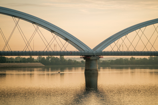 View of the Zezelj Bridge spanning the Danube River during a calm golden hour in Novi Sad Vojvodina Serbia. View of the Zezelj Bridge spanning the Danube River during a calm golden hour in Novi Sad Vojvodina Serbia.