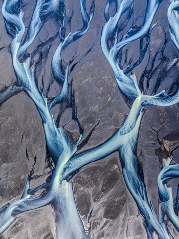 Aerial view of a glacial braided river flowing through dark volcanic sand in Iceland. Aerial view of a glacial braided river flowing through dark volcanic sand in Iceland.