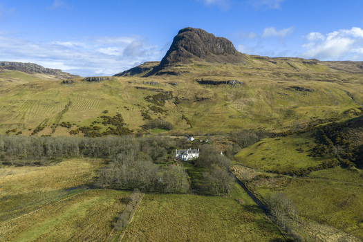 Aerial view of Talisker House nestled among trees at the foot of the Preshal More rocky peak in Isle of Skye Scotland United Kingdom. Aerial view of Talisker House nestled among trees at the foot of the Preshal More rocky peak in Isle of Skye Scotland United Kingdom.