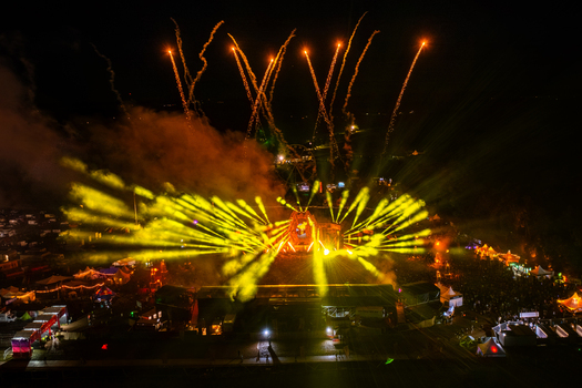 Herzogenaurach Germany 24 July 2025 Aerial view of the Open Beatz Festival stage with bright yellow laser beams and fireworks illuminating the night sky over the crowd.