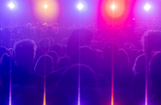 View of a large crowd of people at a concert illuminated by vibrant purple and blue stage lights in Nyon Vaud Switzerland.