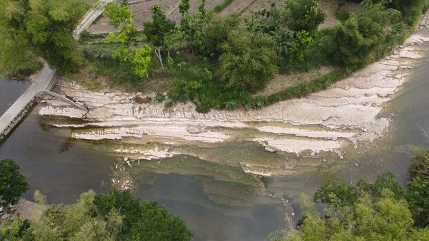 Aerial view of the river with exposed limestone rock formations lush green vegetation and a small bridge in Gunungkidul Regency Special Region of Yogyakarta Indonesia. Aerial view of the river with exposed limestone rock formations lush green vegetation and a small bridge in Gunungkidul Regency Special Region of Yogyakarta Indonesia.