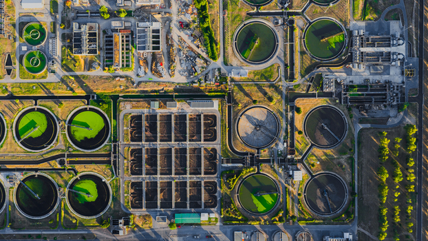 Aerial view of a water treatment plant featuring circular sedimentation tanks and rectangular aeration basins in Rome Lazio Italy.