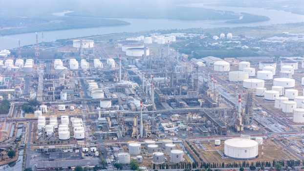 Aerial view of an oil refinery complex with numerous storage tanks intricate pipelines and processing facilities situated along a waterway in Cilacap Central Java Indonesia. Aerial view of an oil refinery complex with numerous storage tanks intricate pipelines and processing facilities situated along a waterway in Cilacap Central Java Indonesia.