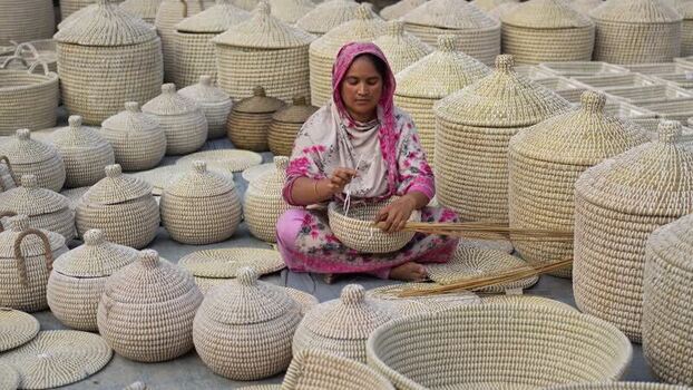 View of a woman weaving traditional baskets in Bogura Bangladesh. View of a woman weaving traditional baskets in Bogura Bangladesh.