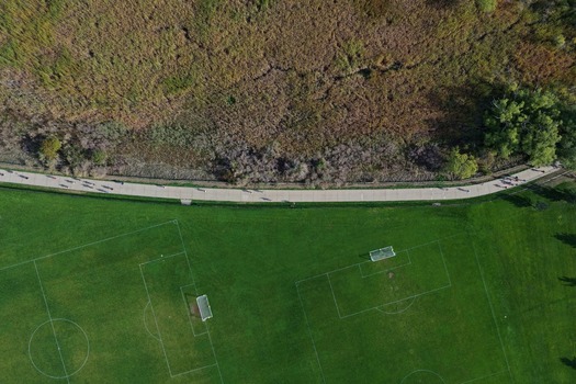 Aerial view of soccer fields and a paved walking path in a park with people exercising in Boulder Colorado United States. Aerial view of soccer fields and a paved walking path in a park with people exercising in Boulder Colorado United States.