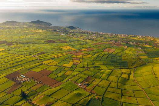 Aerial view of Pico Dona Joana surrounded by a patchwork of green agricultural fields and stone walls overlooking the Atlantic Ocean coastline Feteira Acores Portugal. Aerial view of Pico Dona Joana surrounded by a patchwork of green agricultural fields and stone walls overlooking the Atlantic Ocean coastline Feteira Acores Portugal.